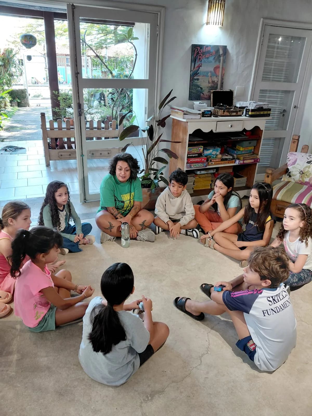 Professora sentada em roda com um grupo de crianças em atividade de inglês