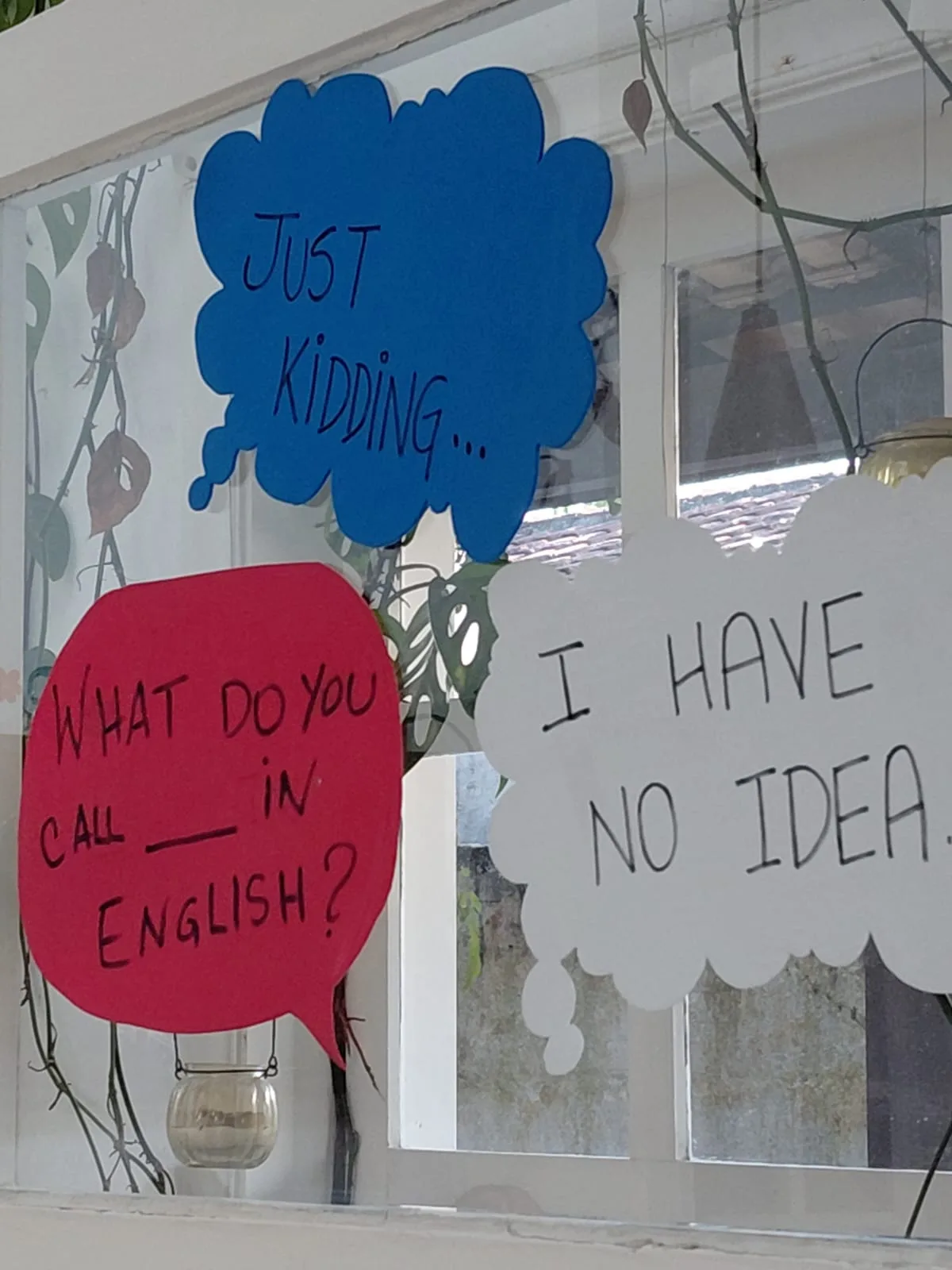 Detalhe de balões de fala em inglês colados na janela da sala de aula